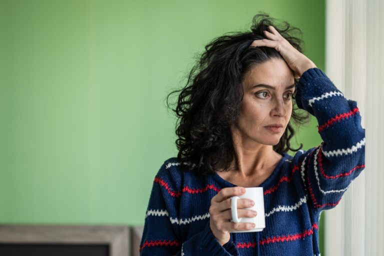 A woman looking stressed and holding a coffee mug
