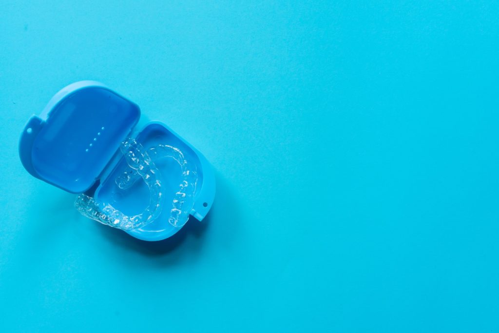 Invisalign clear aligners in a blue protective case on a blue background