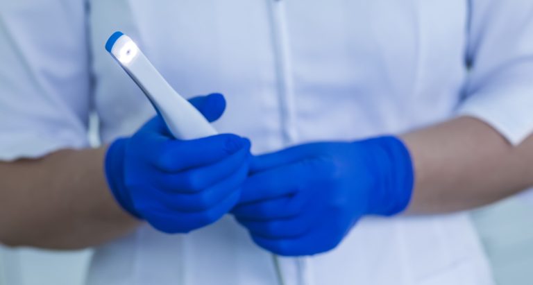 A dental assistant holds an intraoral camera